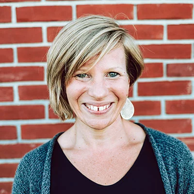 Dr. Meghan Rom smiling in front of a brick wall.